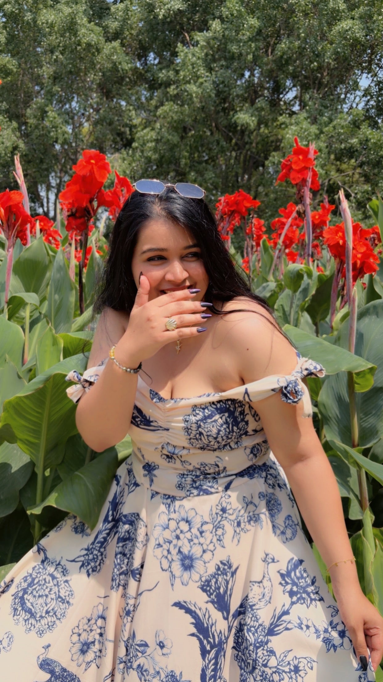 Woman in a floral dress standing in a field of red flowers