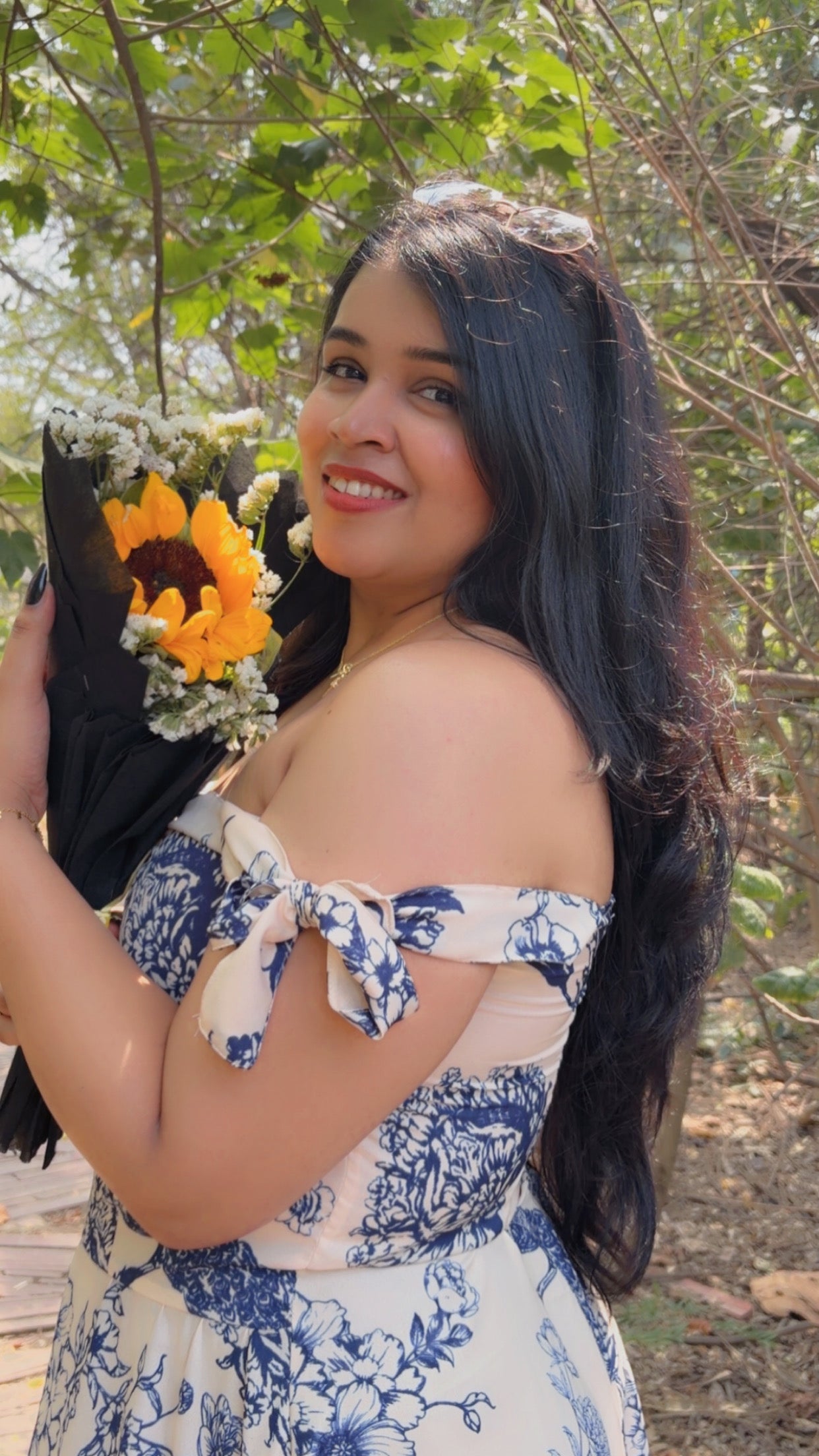 Woman in a floral dress holding a bouquet of flowers outdoors