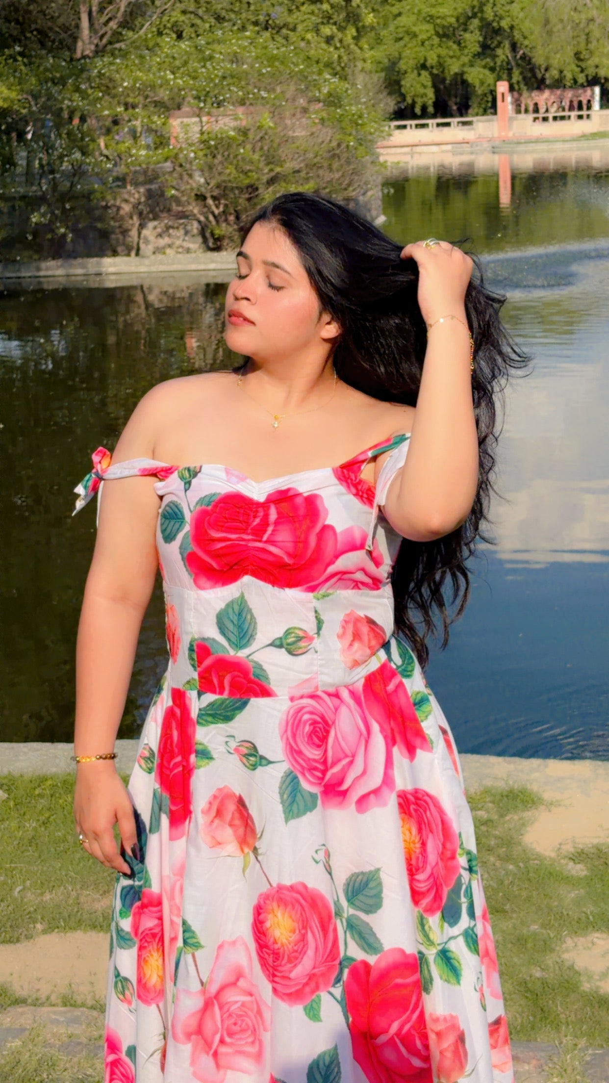 Woman in a floral dress standing by a lake