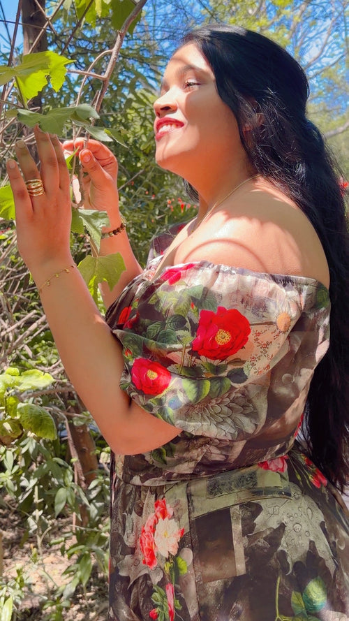 Woman in a floral dress standing outdoors with greenery around