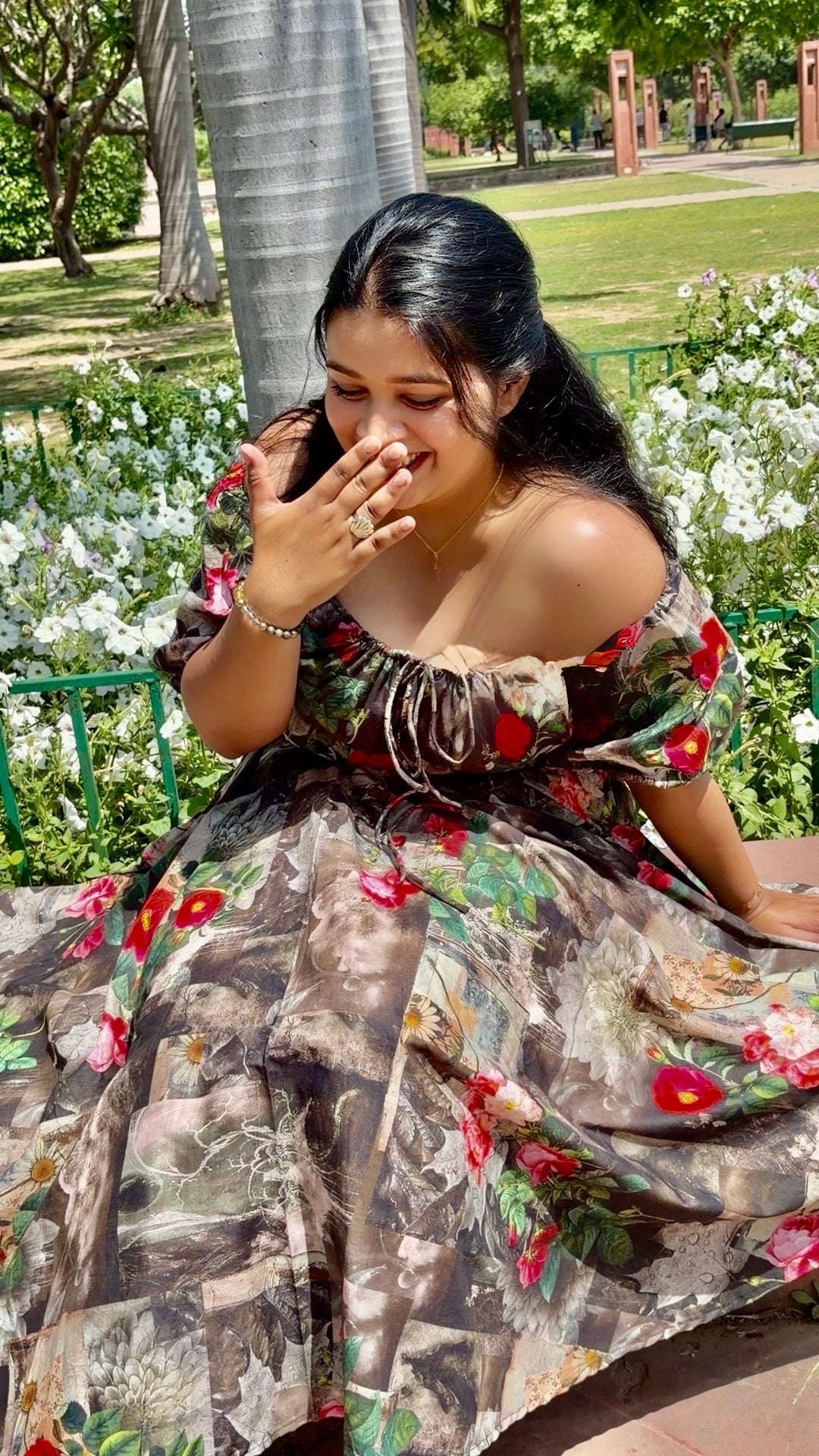 Woman in a floral dress sitting on a bench in a park